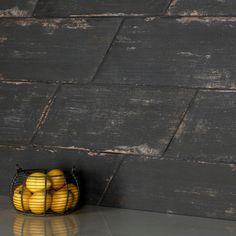 a basket filled with yellow apples sitting on top of a counter next to a wall