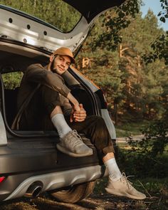 a man sitting in the back of a van with his feet up on the ground