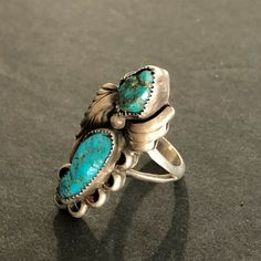 "VINTAGE NAVAJO RING DESCRIPTION: This gorgeous ring is by legendary Navajo artisan David K Lister. Two breathtaking specimens of natural turquoise are secure in micro serrated bezel, flanked by applied leaves, on a foundation oh heavy gauge vintage sterling silver. PLEASE NOTE that the larger of the two cabs has a hairline fissure. The turquoise is secure in its setting. This ring will be a treasured addition to your collection of fine vintage Native American jewelry. MEASUREMENTS: Ring face me Heirloom Turquoise Ring For Collectors, Antique Turquoise Anniversary Ring, Antique Turquoise Adjustable Rings, Vintage Turquoise Open Ring, Untreated Southwestern Turquoise Ring For Anniversary, Unique Turquoise Rings With Patina, Artisan Rings With Patina For Collectors, Handmade Vintage Turquoise Open Ring, Turquoise Ring With Patina For Anniversary