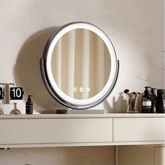 a round mirror sitting on top of a white dresser next to a bottle and other items