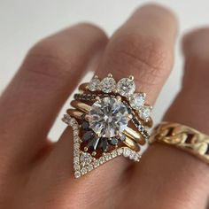 a woman's hand with two rings on it and an engagement ring in the middle