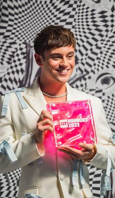 a man in a white suit holding up a pink package