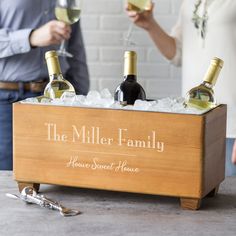 two people holding wine glasses in a wooden box with live love wine written on it