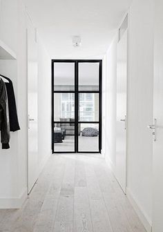 an empty white hallway with black glass doors