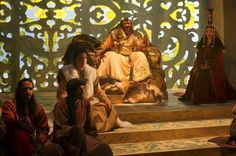 three people dressed in costumes sitting on a stage