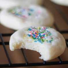 three cookies with sprinkles are on a cooling rack