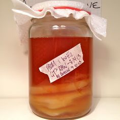 a jar filled with liquid sitting on top of a white counter next to a piece of paper