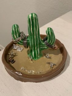 a green cactus plant sitting on top of a table next to other small objects in a bowl