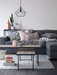 a living room with grey couches and pillows on top of the rugs in front of them