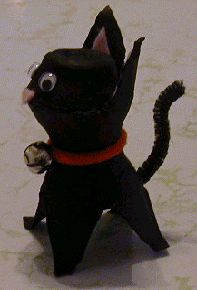 a black cat figurine sitting on top of a white floor next to a wall