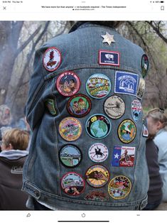 a person wearing a jean jacket with many different patches on it and the back of their jacket