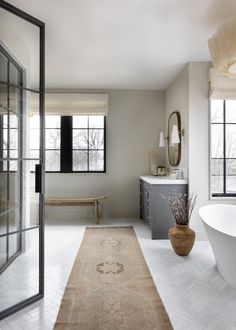 a bath room with a tub a sink and a large rug on the floor in front of a window