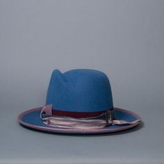 Western weight fedora with sculpted crown and upturned brim. Trimmed with mix-match grosgrain band and bow, silk sari ribbon and vintage silver buckle. Brim edge is bound with mauve grosgrain. Materials: Ethically sourced 160 g rabbit fur felt, Grosgrain, Silk, Metal Style: Western Fedora Measurements: Crown height at center front 5 in (13 cm) Brim 3 in (7.5 cm) Hat Box: 16 in How to Wear: Classic fit Ready to ship in a size 22.5 in / 57 cm / men's 7-1/8 with slightly-wider oval profile. One of Luxury Blue Short Brim Hat, Formal Hat With Ribbon And Curved Brim, Elegant Blue Fedora Felt Hat, Formal Blue Fedora Hat, Elegant Blue Felt Hat With Flat Brim, Elegant Blue Fedora With Short Brim, Elegant Blue Wide Brim Fedora, Elegant Adjustable Blue Hat Band, Blue Curved Brim Top Hat For Formal Occasions