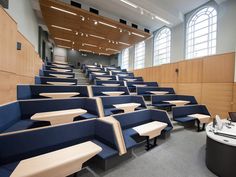 an empty lecture hall with blue seats and tables