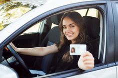 a woman sitting in the driver's seat of a car taking a selfie with her phone