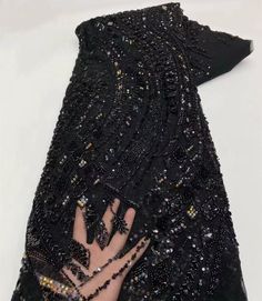 a woman's hand is covered with black sequins and beaded gloves