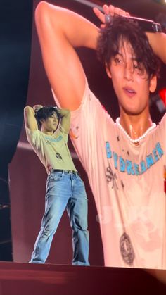 a young man holding his head while standing on top of a stage next to another person