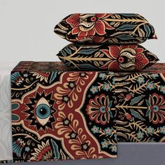 three pillows stacked on top of each other with an ornate design in the middle and blue eyes