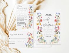 the wedding stationery is laid out on top of a white tablecloth with flowers