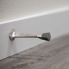 a close up of a door handle on a white wall with wood flooring in the background