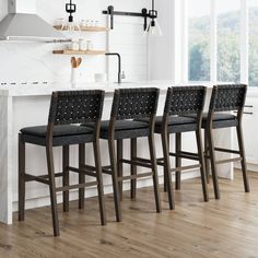 four black leather bar stools are lined up in front of an island with marble countertops