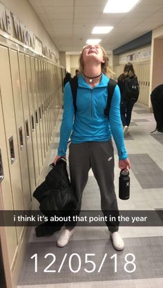 a woman standing in a hallway with her back to the camera and holding two backpacks