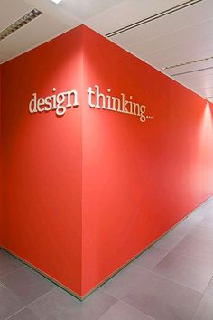 a red wall with the words design thinking on it in front of a white ceiling