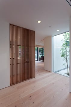 an empty room with wooden slats on the wall and wood flooring in front of it