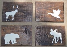 four wooden coasters with white moose and deer silhouettes on them, sitting on a table