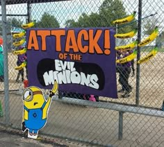 a fence with a sign that says attack of the evil minions on it and some people behind it