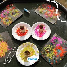 four paper plates with flowers on them sitting on a black table next to two cups