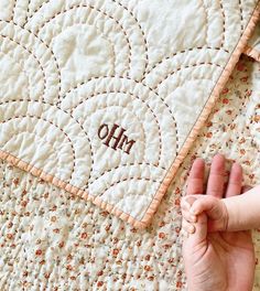 a baby's hand on top of a quilted blanket with the word oh