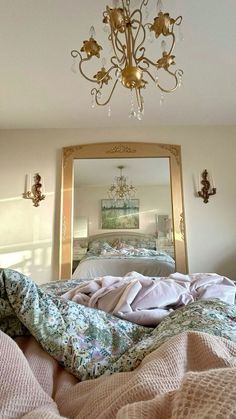 a chandelier hanging from the ceiling above a bed covered in blankets and pillows