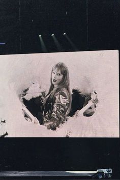 a woman standing in front of a large screen with lights on it's sides