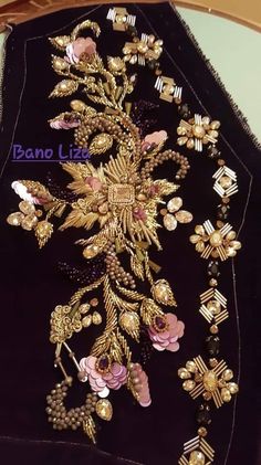 a black velvet jacket with gold and pink flowers on the front, along with other brooches