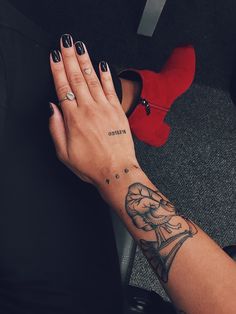 a woman's hand with a tattoo on her left wrist and red high heels