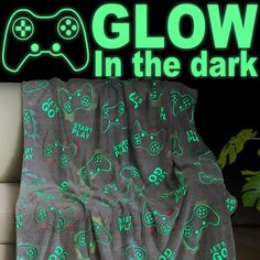 glow in the dark blanket with video game controllers on it, sitting on a couch