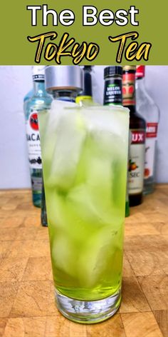 a green drink with ice in it on top of a wooden table