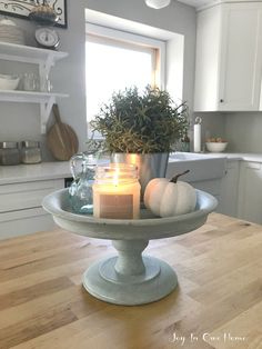 a candle is sitting on top of a cake plate in the middle of a kitchen