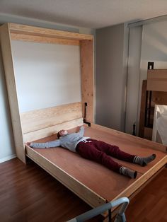 a person laying on top of a bed in a room with wooden floors and walls