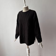 a white mannequin wearing a black sweater on top of a dress form stand