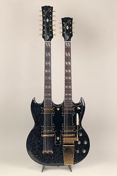 two electric guitars sitting side by side on top of each other in front of a white background