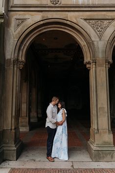 a man and woman standing in front of an archway