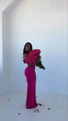 a woman in a pink dress holding a large bouquet of flowers and posing for the camera