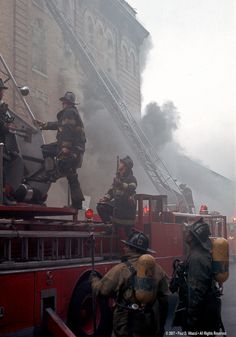 firemen are on top of a firetruck with their hoses in the air