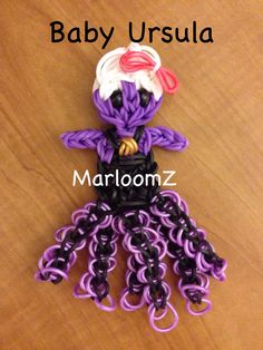 a purple and black octopus made out of plastic beads on top of a wooden table