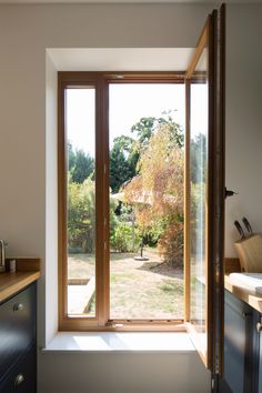 an open window in a kitchen next to a wooden counter top and cabinet with drawers