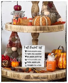 a three tiered tray filled with lots of fall decorations and fruit on top of it