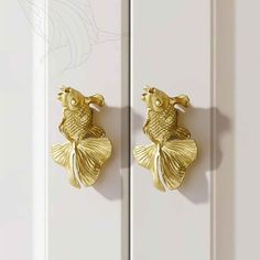 two gold fish hooks on the side of a white door