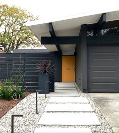 a modern house with black siding and yellow door